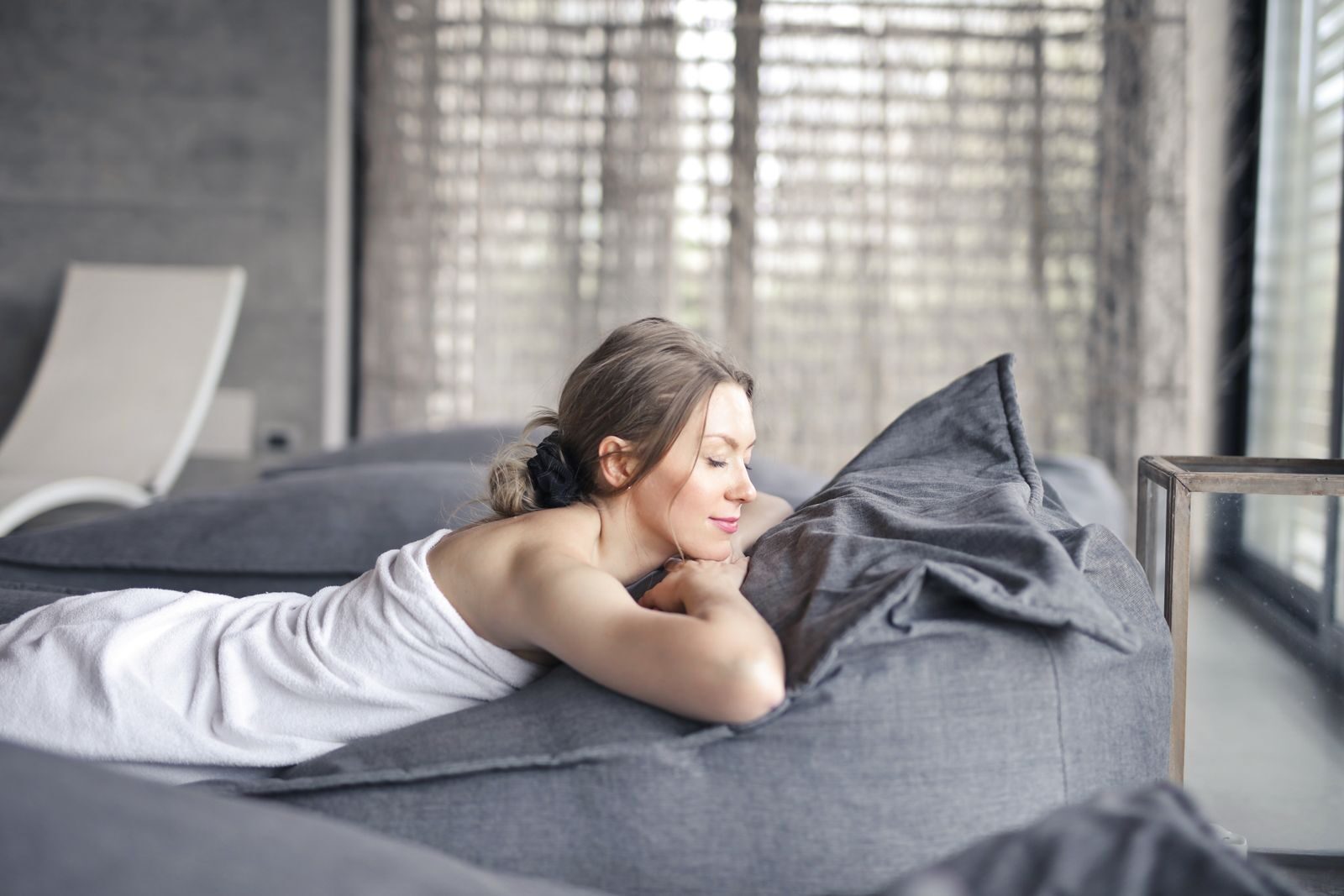 A woman wrapped in a towel resting with her eyes closed