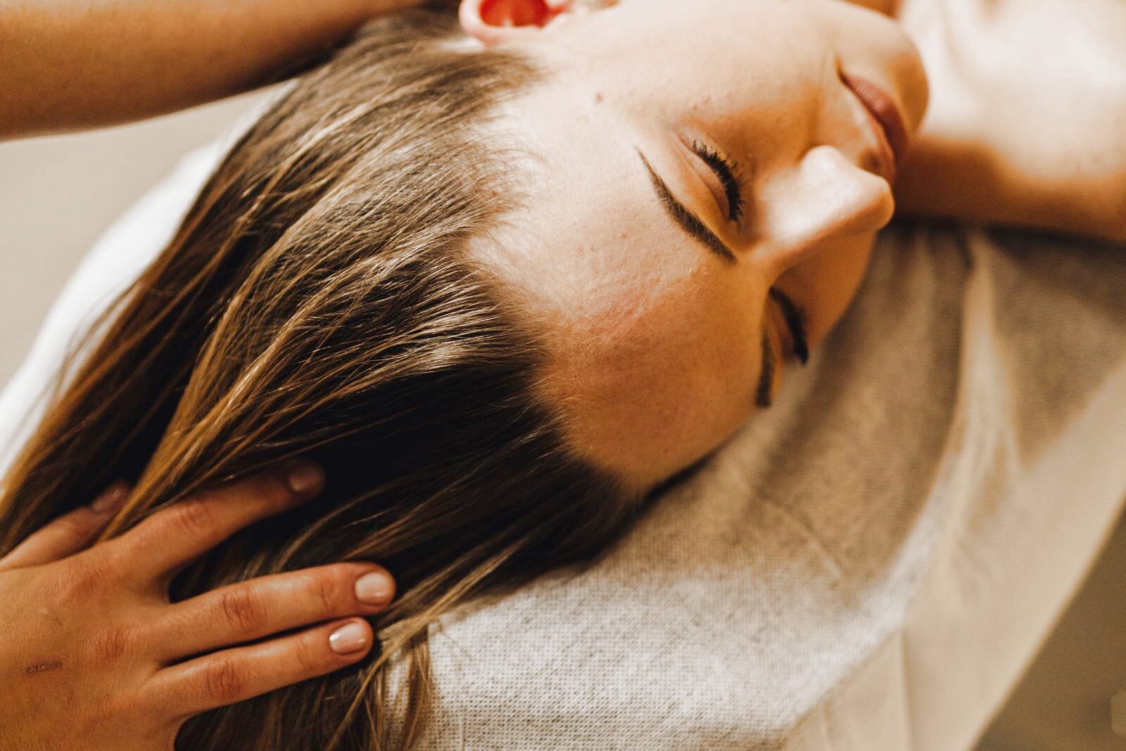 A therapist's fingers massaging a woman's scalp through her hair