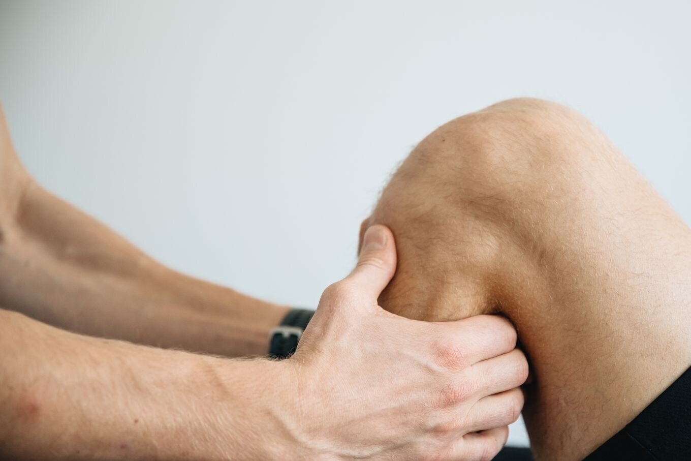 A therapist's hands working around the side of a knee