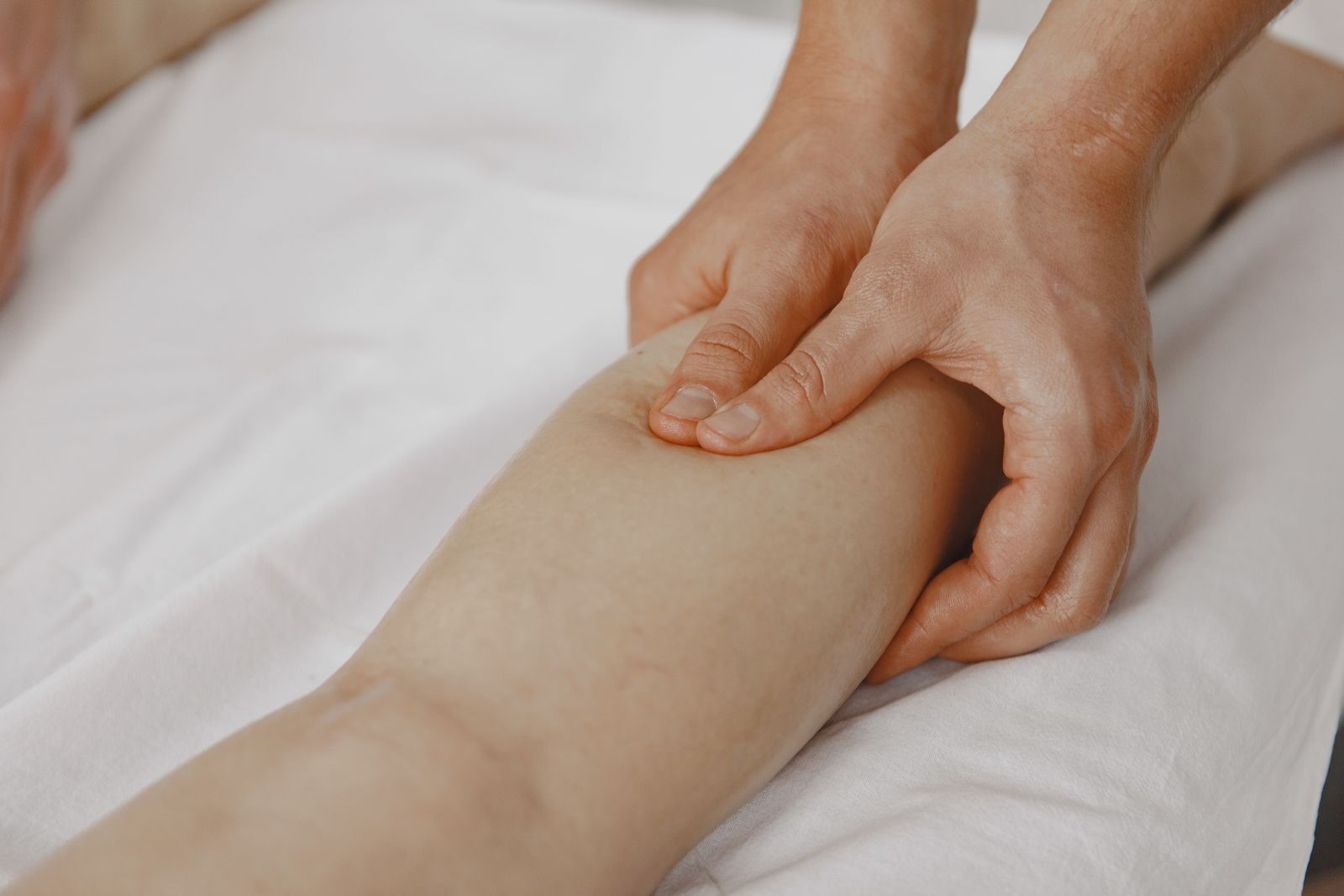 A therapist's hands resting lightly on a person's lower leg during a gentle massage